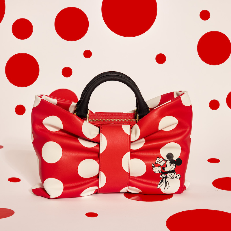 Minnie Rocks the Dots Classic Bow Figural Crossbody sitting in the middle of a white background with red polka dots all over it